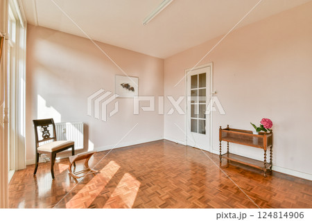 A bright, minimalist interior featuring a wooden floor, a single chair, and subtle decor elements that emphasize spaciousness and natural light. A bright, minimalist interior featuring a wooden floor, a single chair, and subtle decor elements that emphasize spaciousness and natural light. 124814906
