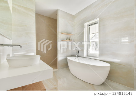 Elegant modern bathroom showcasing a freestanding tub, sleek cabinetry, and warm lighting, creating a relaxing atmosphere. Perfect for contemporary home decor inspiration. 124815145