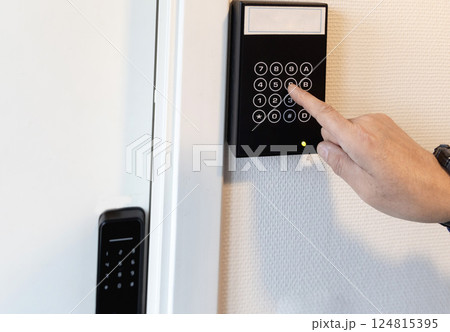 A human hand presses buttons with numbers to enter a code to open the door. A human hand presses buttons with numbers to enter a code to open the door. 124815395