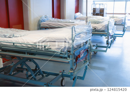Clean hospital beds covered with film, ready for new patients. Clean hospital beds covered with film, ready for new patients. 124815420