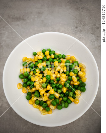 Small white ceramic bowl containing steamed green peas and golden corn kernels, resting on neutral grey surface copy space Galentines day Small white ceramic bowl containing steamed green peas and golden corn kernels, resting on neutral grey surface copy space Galentines day 124815716