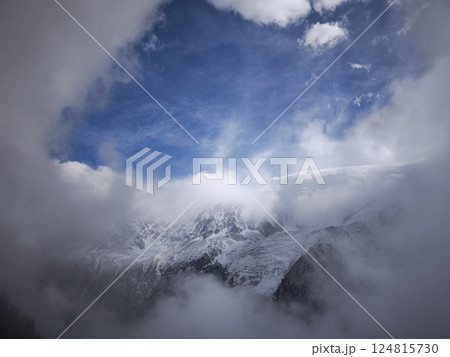 Snow covered mountains in chamonix, france, clouds under a blue sky, creating a dramatic natural scene 124815730