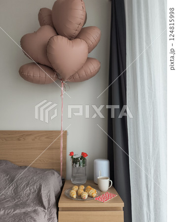 Heart shaped balloons, fresh roses, and pastries create a romantic valentine's day breakfast surprise beside a cozy bed Heart shaped balloons, fresh roses, and pastries create a romantic valentine's day breakfast surprise beside a cozy bed 124815998