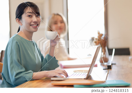 カフェでコーヒーを飲みながら仕事する若い女性 カフェでコーヒーを飲みながら仕事する若い女性 124818315