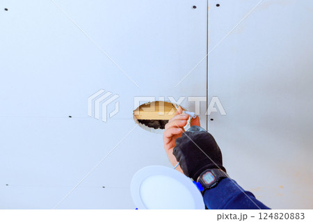 Electrician contractor engages by applying service installation led lamp at ceiling hole 124820883