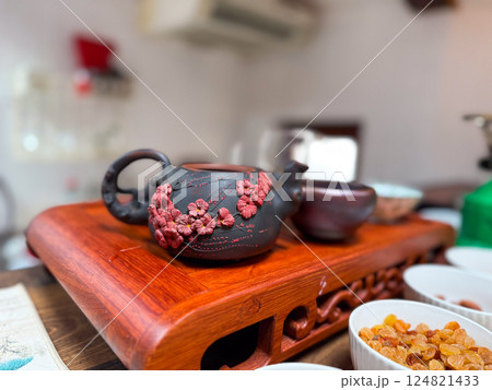 Clay teapot with cherry blossom detail on wooden tray during tea session. Traditional tea ceremony and cultural appreciation Clay teapot with cherry blossom detail on wooden tray during tea session. Traditional tea ceremony and cultural appreciation 124821433