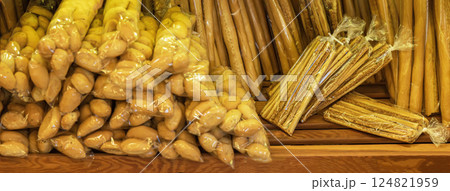 Packed breadsticks and bread rolls arranged on wooden shelves inside local bakery. Colorful selection of bread products in bakery pastry shop 124821959