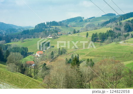 Serene landscape of rolling hills and charming cottages under a crisp blue sky in rural countryside during early spring 124822058