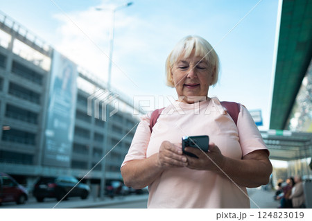 Senior woman checking smartphone outside the airport 124823019