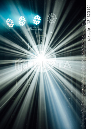 A mirrored disco ball reflects light rays throughout the room. Smoke enhances the visibility 124823194