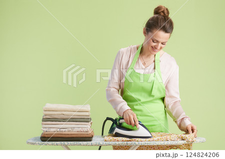 Woman ironing patterned fabric, pastel green backdrop 124824206