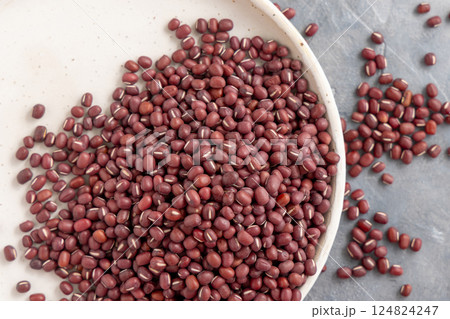 Plate full of dried red azuki beans on gray top view. East Asian legumes, vegetarian protein source Plate full of dried red azuki beans on gray top view. East Asian legumes, vegetarian protein source 124824247