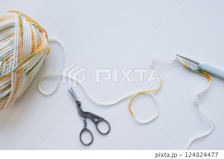 Colorful yarn ball with crochet hook and scissors on white background 124824477