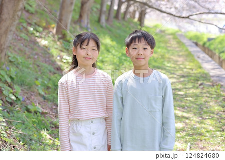 春の公園に立つ小学生男女 124824680