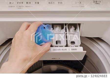 洗濯機の洗剤ケースに液体洗剤を投入する手 124824883