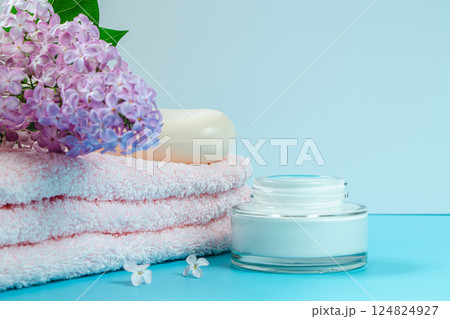 Spa and skin care concept. Towel, cream and soap on background of delicate lilac flowers. Spa and skin care concept. Towel, cream and soap on background of delicate lilac flowers. 124824927