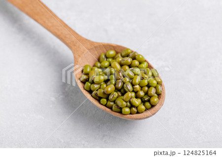 Healthy mung beans in a wooden spoon on grey table background Healthy mung beans in a wooden spoon on grey table background 124825164