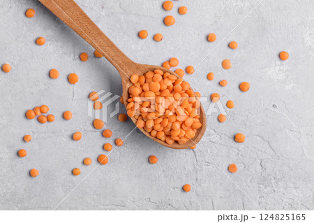 Organic red lentil on wooden spoon, close up Organic red lentil on wooden spoon, close up 124825165