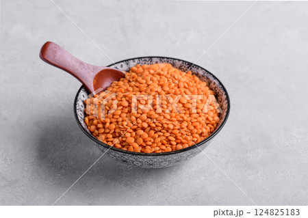 Dry red lentils in bowl with spoon on grey background Dry red lentils in bowl with spoon on grey background 124825183