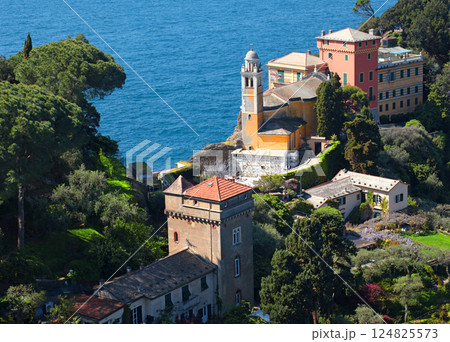 Portofino, Italy - 07 April 2025. Church in bay of Liguria. Sea and tourism in Italy. Traditional buildings. Background for design. Portofino, Italy - 07 April 2025. Church in bay of Liguria. Sea and tourism in Italy. Traditional buildings. Background for design. 124825573