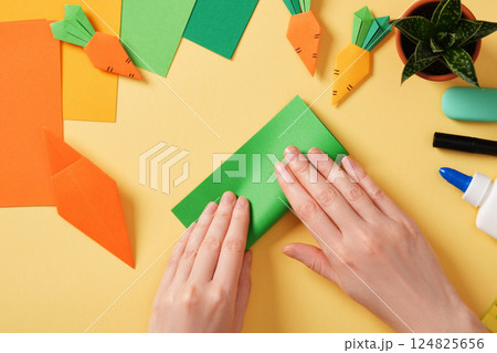Making a simple origami carrot Easter craft. Fold the green piece of paper four times. Around the paper creativity tools. 124825656