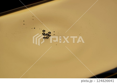 Texture of cosmetic oil on a gold background. Texture of cosmetic oil on a gold background. 124826641
