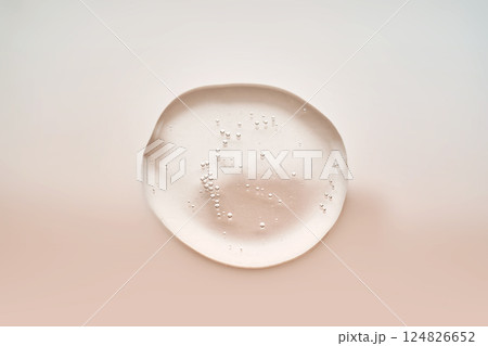 Textured drop of serum with bubbles on pink background. Textured drop of serum with bubbles on pink background. 124826652