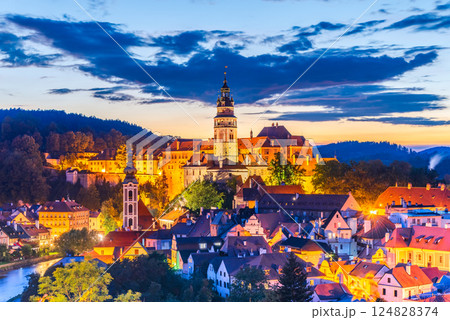 Cesky Krumlov, Czech Republic. Twilight glows with golden lights, its medieval oldtown towering over winding cobblestone streets, Bohemia heritage. 124828374