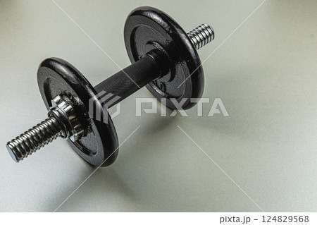Black dumbbell on a gray surface for fitness training Black dumbbell on a gray surface for fitness training 124829568