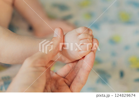 Father's hand gently holding his baby's tiny foot, symbolizing love, protection, and family bond. Parenthood, care, and tenderness concept 124829674
