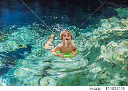 Young boy exploring a stunning Mexican cenote with turquoise water. Adventure, travel, and nature discovery concept Young boy exploring a stunning Mexican cenote with turquoise water. Adventure, travel, and nature discovery concept 124831006