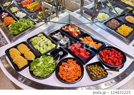 A salad bar featuring an extensive variety of fresh vegetables and fruits A salad bar featuring an extensive variety of fresh vegetables and fruits 124831225