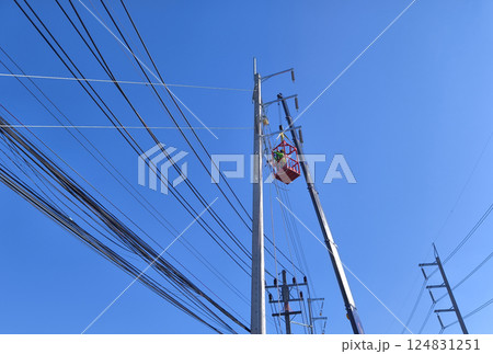 Men in work clothes and hard hats are installing high-voltage wires on a power pole Men in work clothes and hard hats are installing high-voltage wires on a power pole 124831251