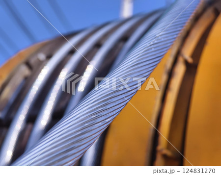 A large wooden spool of high-voltage electric wires is located on the road 124831270