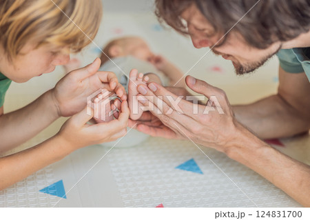 Father, son, and newborn baby lying on the floor in a cozy nursery, celebrating the arrival of their newest family member. Parenthood, bonding, and family love concept 124831700