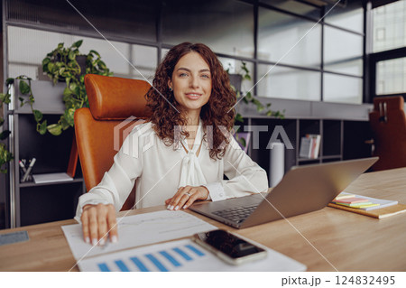 A dedicated professional woman is focused on her work at her desk in a modern office setting 124832495