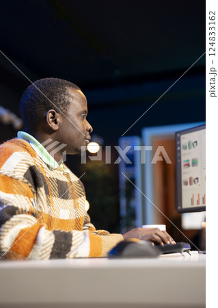 Entrepreneur doing remote work using monthly revenue balance, examining statistics at his workstation. Investment advisor planning new strategy to obtain more funds for global development. Entrepreneur doing remote work using monthly revenue balance, examining statistics at his workstation. Investment advisor planning new strategy to obtain more funds for global development. 124833162