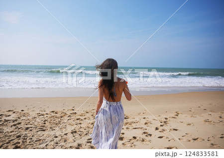 Woman cheers with cocktail on beach during sunny seaside celebration 124833581