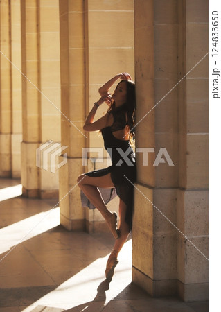 Ballet dancer posing in warm sunlight arcade 124833650