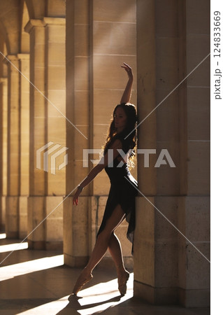 Ballerina in elegant pose under sunlit arches Ballerina in elegant pose under sunlit arches 124833669