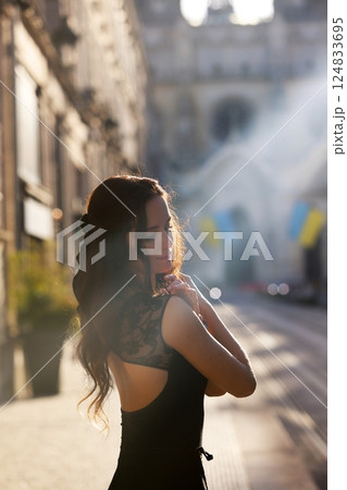 Elegant woman in sunlight on city street 124833695