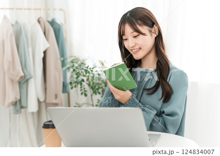 オフィスオフィス,仕事場でメモ帳,ネタ帳を見る笑顔の若いアジア人女性 124834007