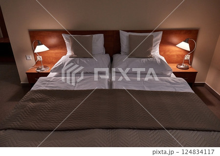 Hotel bed with white sheets, cozy lighting 124834117