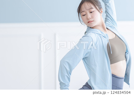 長袖を着て明るい部屋でストレッチをする若い女性 124834504