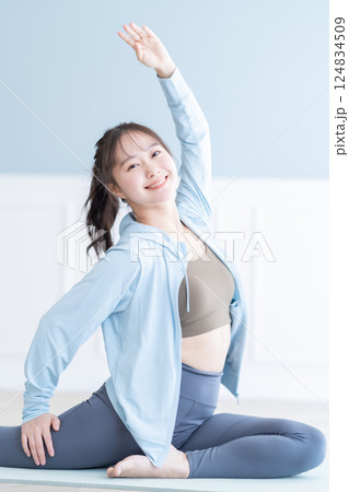 長袖を着て明るい部屋でストレッチをする若い女性 124834509