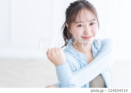 長袖を着て明るい部屋でストレッチをする若い女性 長袖を着て明るい部屋でストレッチをする若い女性 124834514