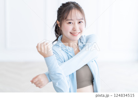 長袖を着て明るい部屋でストレッチをする若い女性 124834515