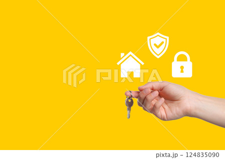 Hand holding keys with icons representing home security and protection in vibrant yellow Hand holding keys with icons representing home security and protection in vibrant yellow 124835090