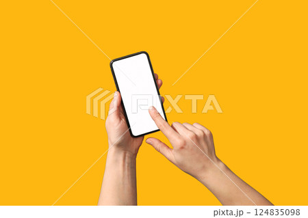 Hands interact with a modern smartphone against a vibrant yellow background Hands interact with a modern smartphone against a vibrant yellow background 124835098