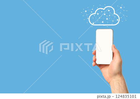 A person with a smartphone displaying a cloud icon on a blue background 124835101